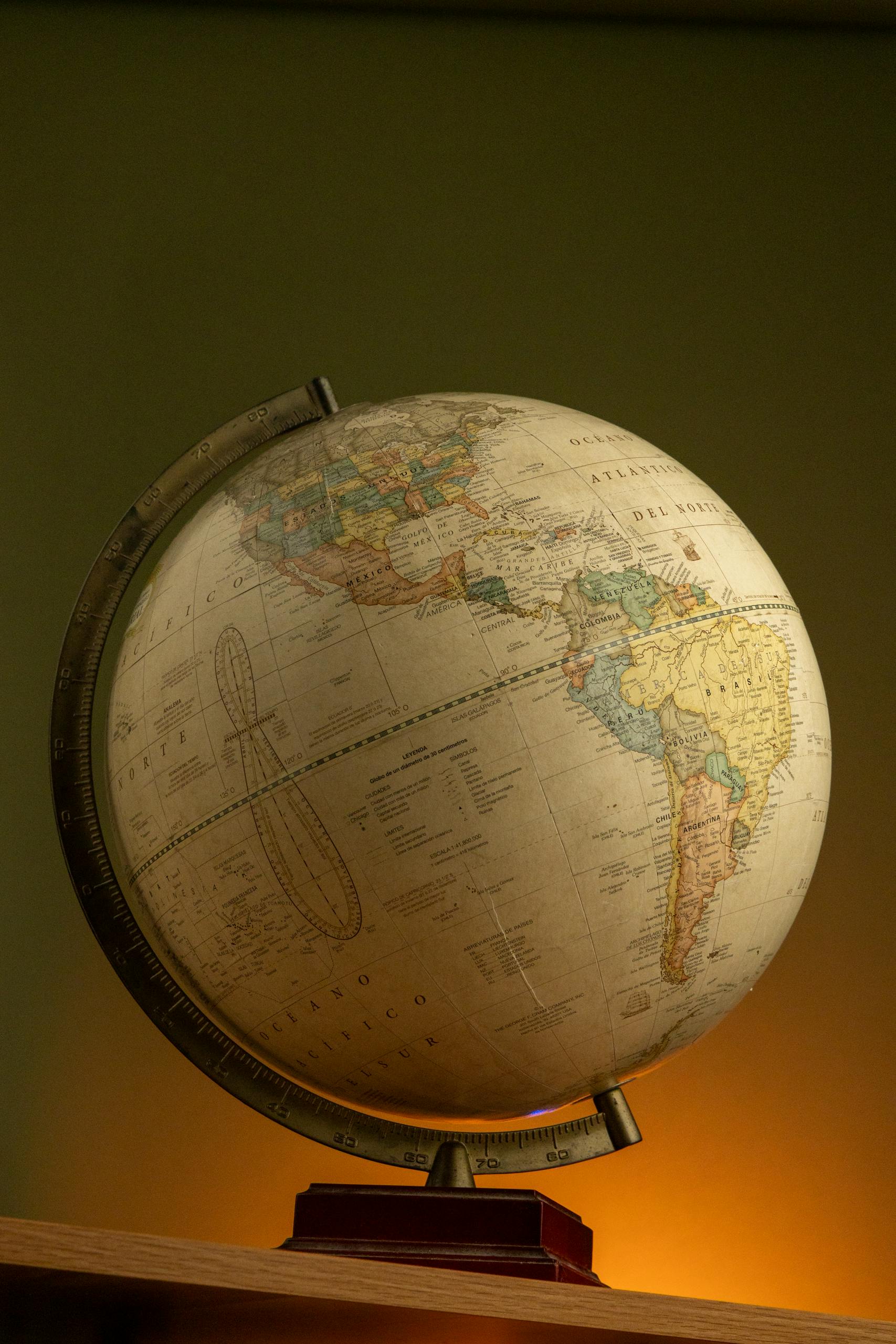 A classic globe depicting North and South America, warmly lit on a wooden base.